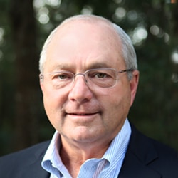 Male in suit and glasses smiling at the camera