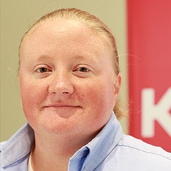 Female with hair pulled back smiling close-lipped at the camera