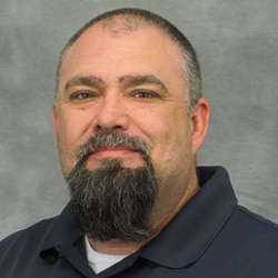 Man with goatee smiling close-lipped at the camera